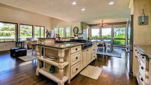 Une cuisine spacieuse dotée d’un grand îlot central, de meubles en bois et d’un coin repas offrant une vue agréable.