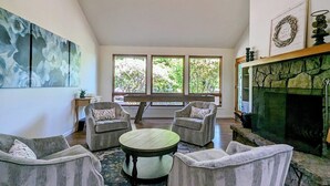 Un salon avec une cheminée, deux fauteuils, une table basse ronde et un grand tableau abstrait.