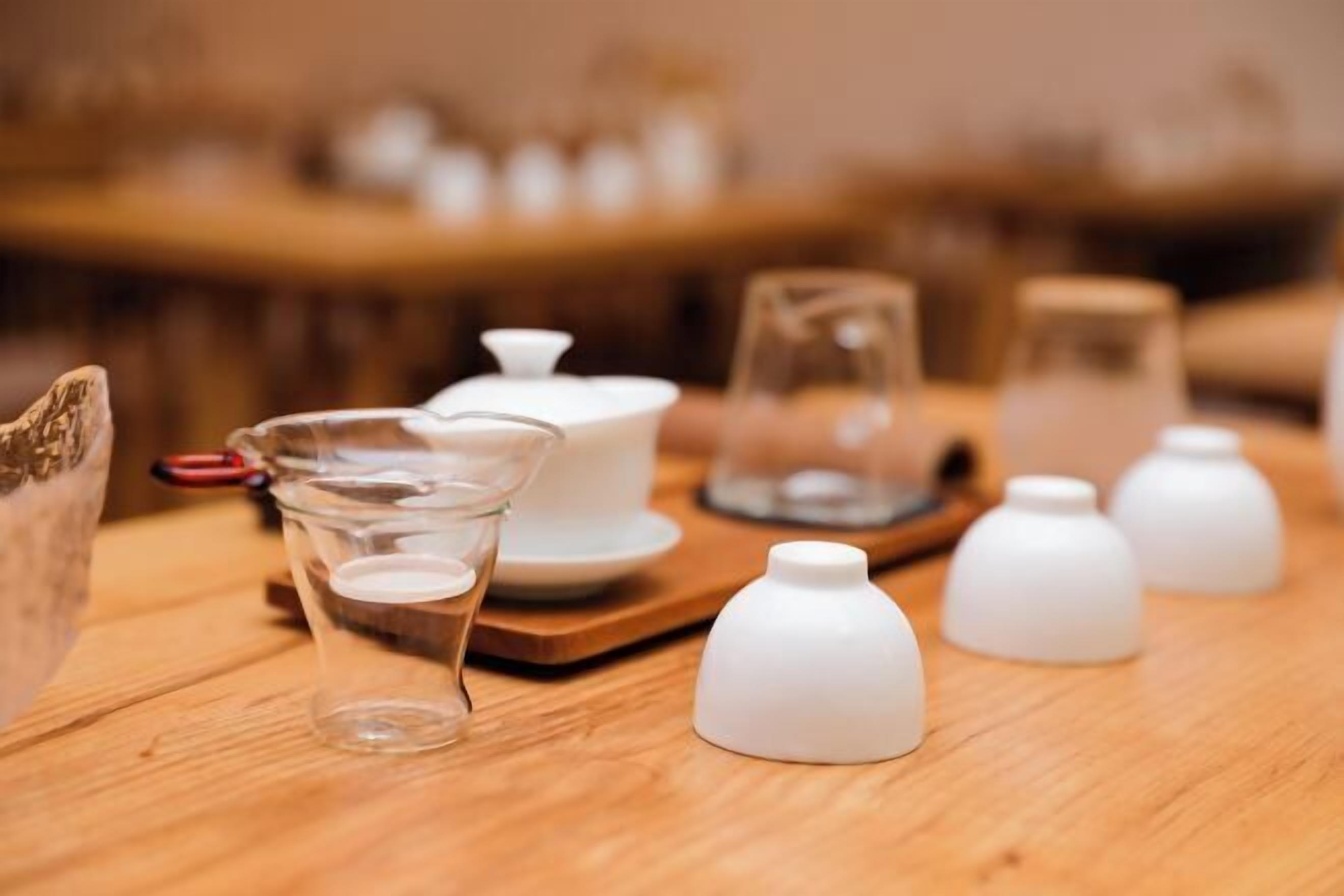 A wooden table with various white ceramic items, including a glass pitcher, a teapot, and several small vases.