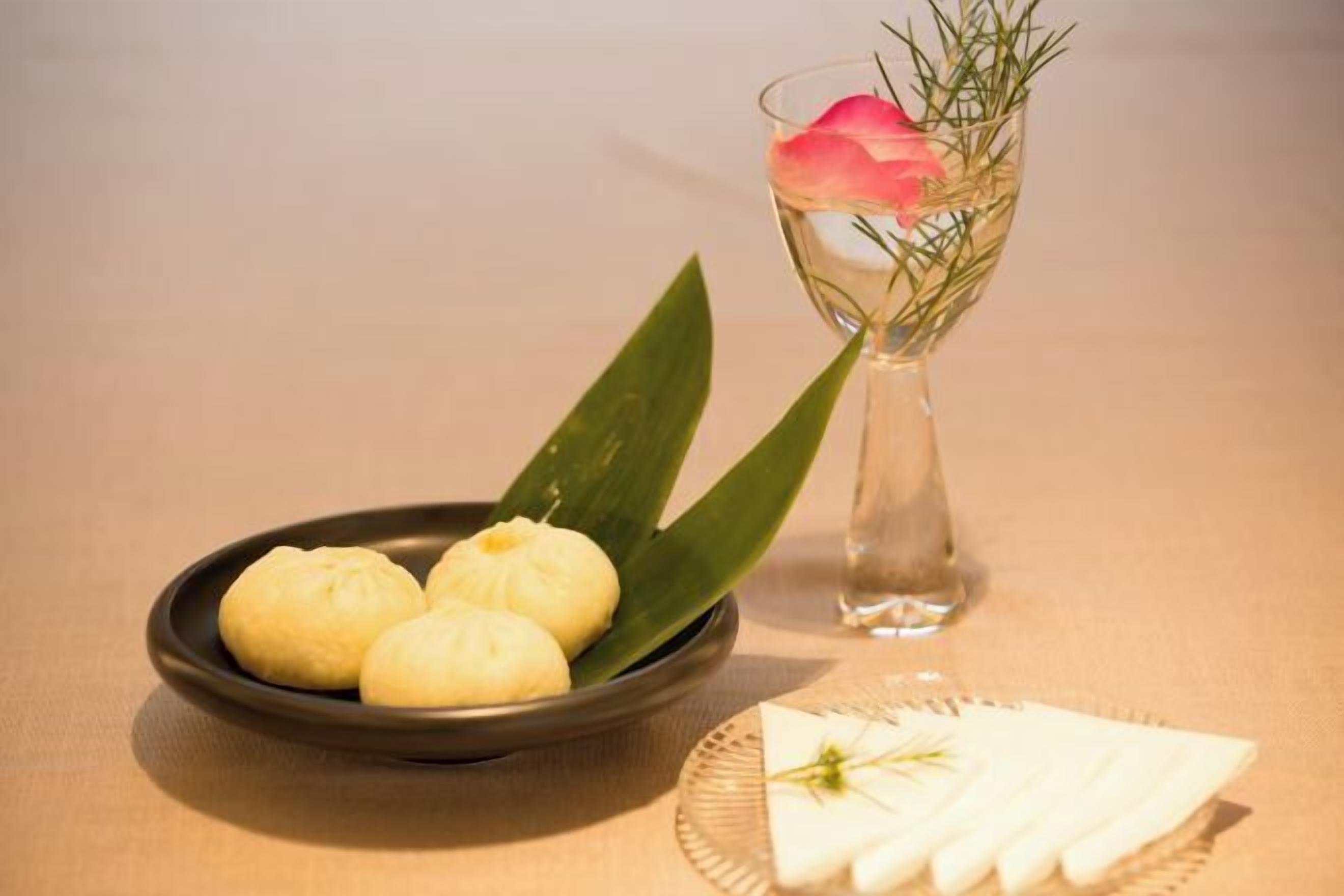 Eine Schüssel Essen, ein Glas mit einer Blume und ein Teller mit einer Serviette auf einem Tisch.