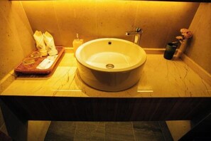 A bathroom with a round sink, a mirror, a towel rack, and toiletries on the counter. - Qianfoshan Jiankang Hotel (Suichang)