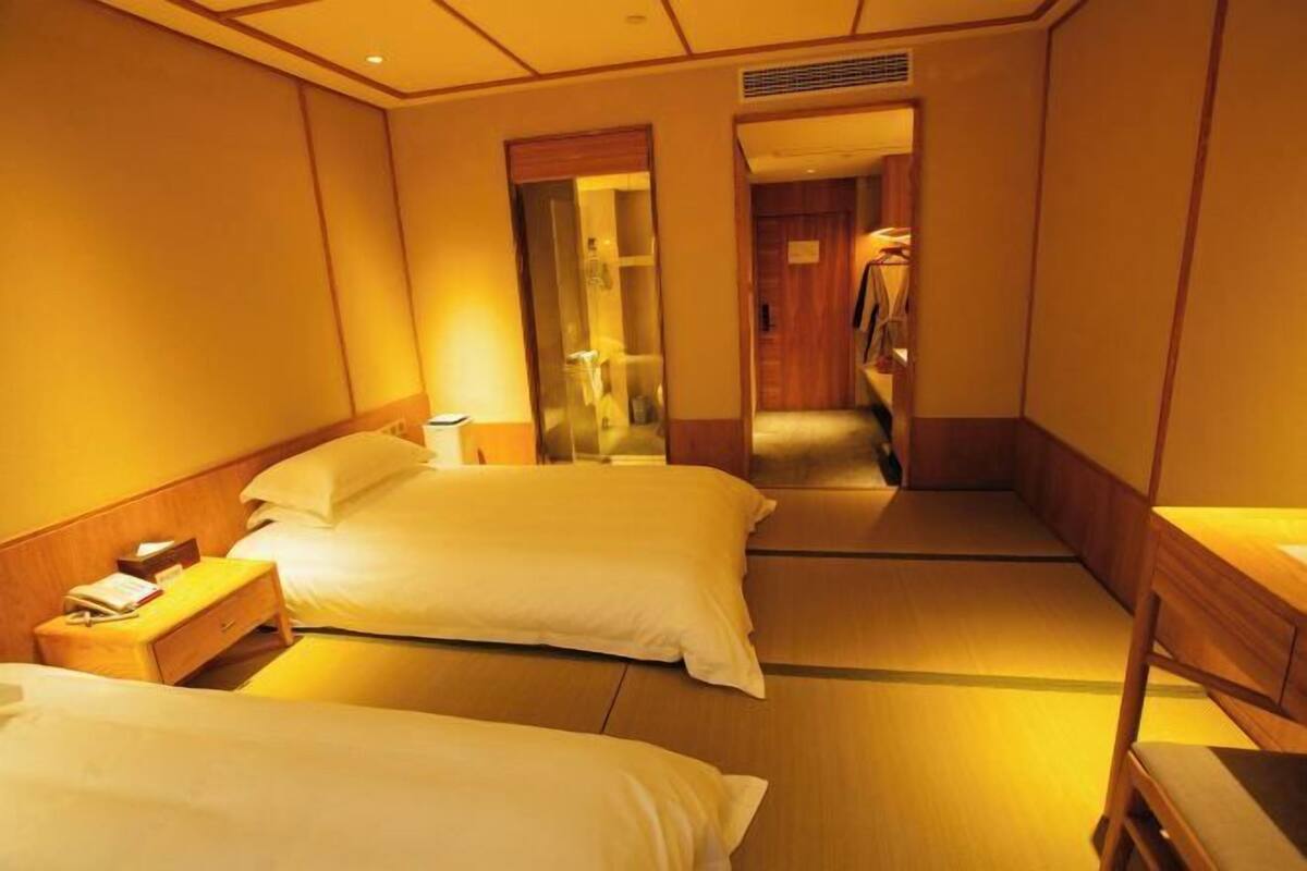 Une chambre d’hôtel avec deux lits, une table de chevet en bois, une petite table et un miroir.