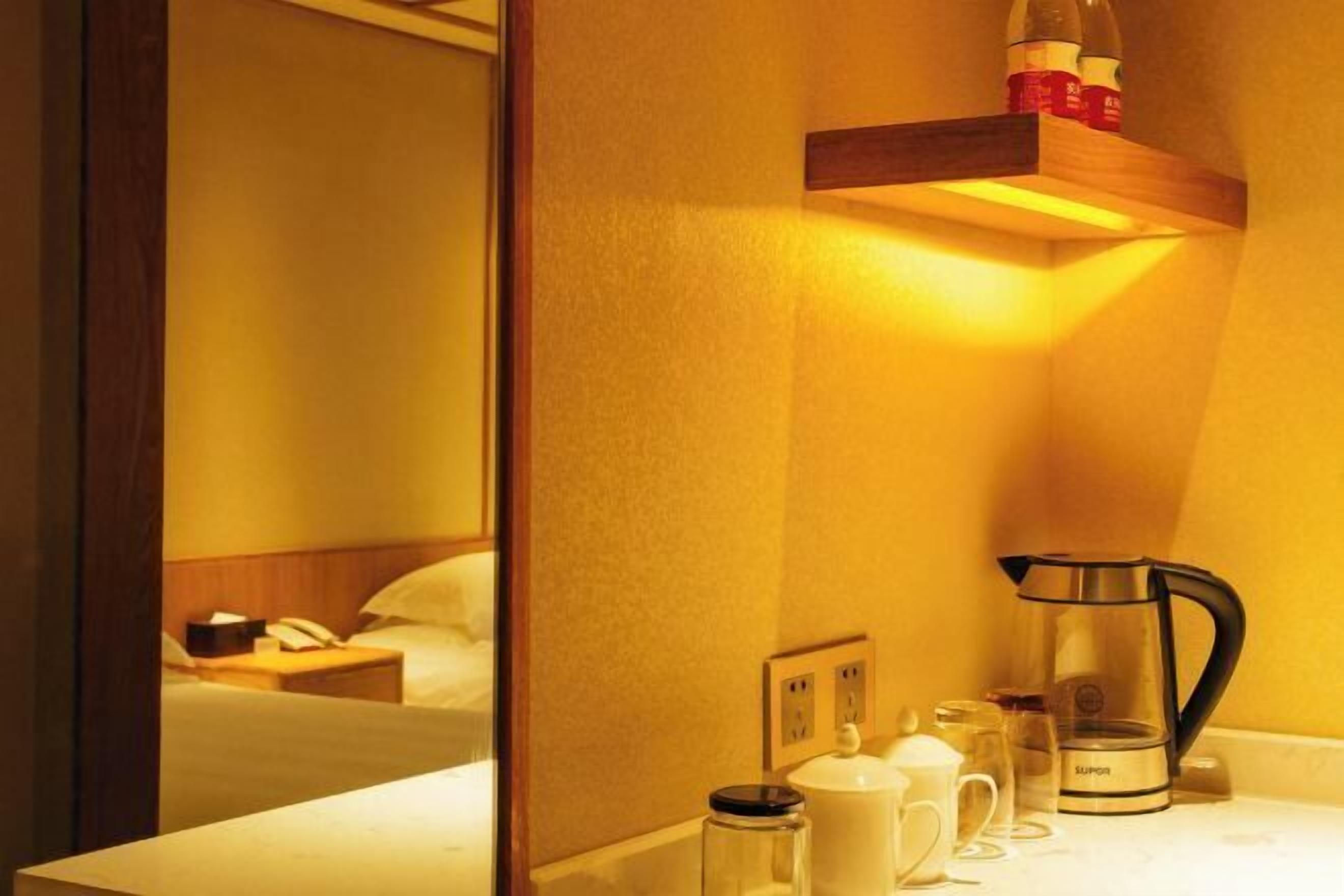 A hotel room with a bed, bedside table, and a coffee maker on the counter.