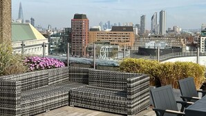 Eine Dachterrasse mit Sitzgelegenheiten und Blick auf die Stadt.