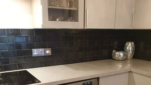 Eine kompakte Küche mit Einbauofen, Waschmaschine und einer Arbeitsplatte mit Glaskabinett darüber.