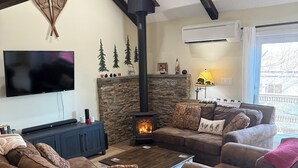 A living room with a fireplace, sofas, a TV, and a ceiling fan. - Escape to the Pocono Mountains. (Tannersville)