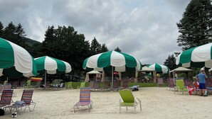 A beach with rows of sun loungers and green and white umbrellas providing shade. - Escape to the Pocono Mountains. (Tannersville)