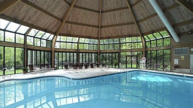 A large indoor swimming pool with a high ceiling and large windows. - Escape to the Pocono Mountains. (Tannersville)
