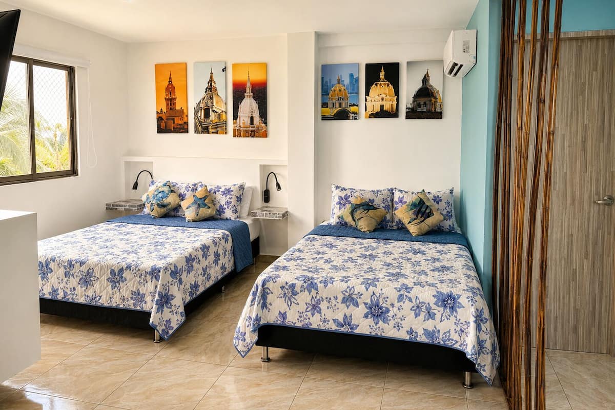 Une chambre d’hôtel avec deux lits, une fenêtre et des œuvres d’art accrochées au mur.