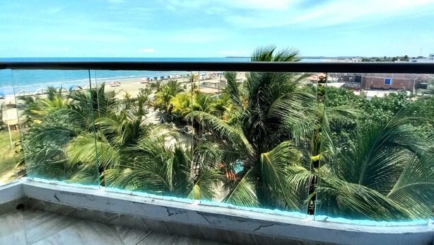 A balcony with a view of a beach and palm trees. - Hotel Avadia Del Mar (Cartagena)