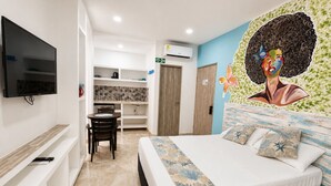 A hotel room with a bed, a TV, a desk, and a mural on the wall. - Hotel Avadia Del Mar (Cartagena)