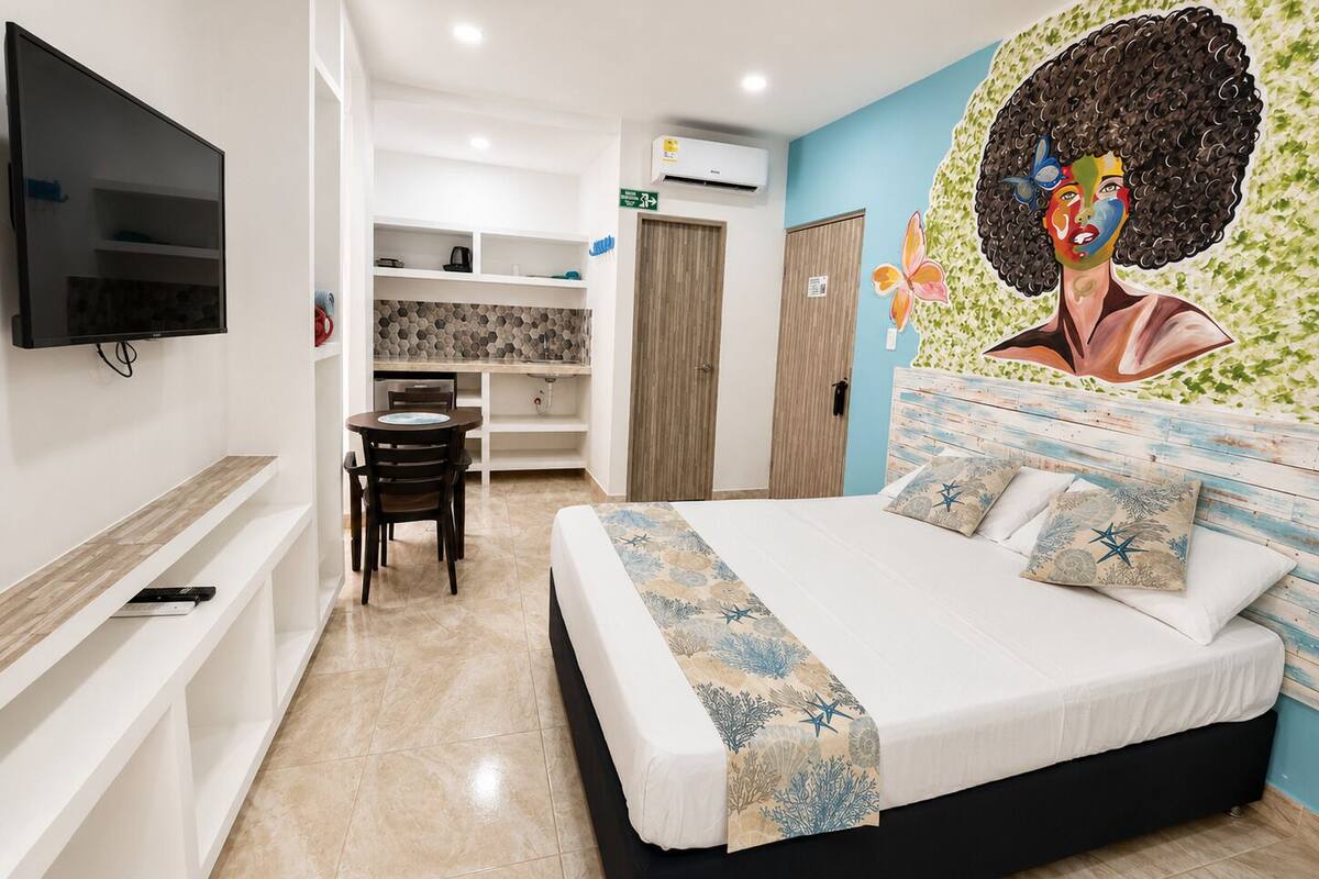 Une chambre d’hôtel avec un lit, une télévision, un bureau et une fresque murale.