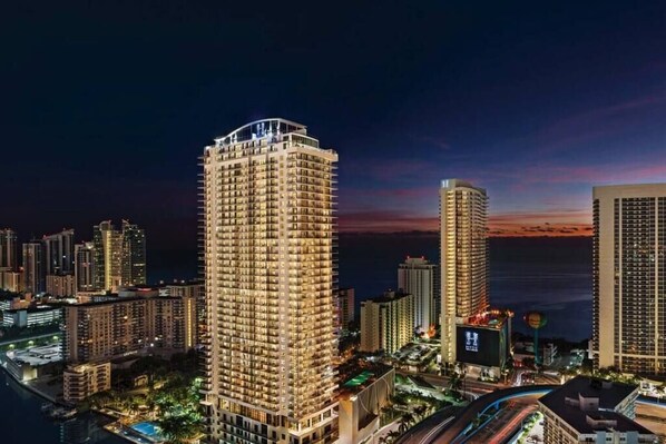 Un grand hôtel à plusieurs étages, entouré d’autres immeubles et bordé par un plan d’eau.