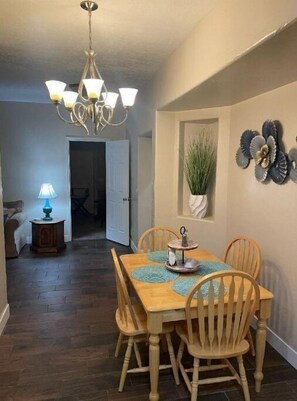 Enjoy meals in this cozy dining area with a wooden table and matching chairs, a chandelier, and a side table with a lamp.