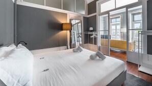 Una camera d'albergo con un letto grande, una lampada da comodino, un armadio e un balcone con una sedia gialla.