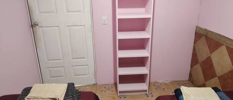A bedroom with two beds, a wardrobe, and a door.