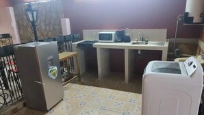 A compact kitchen with a refrigerator, microwave, sink, and washing machine.