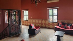 A spacious living room with a staircase, two sofas, a table, and a chandelier.