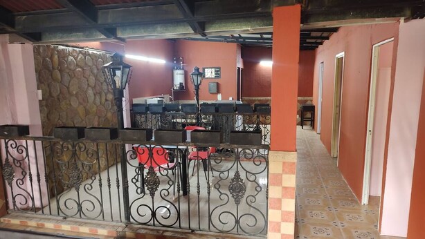 A room with a stone wall, a metal gate, and a tiled floor.