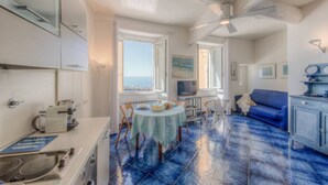A kitchen with a dining area, a ceiling fan, and a view of the sea.