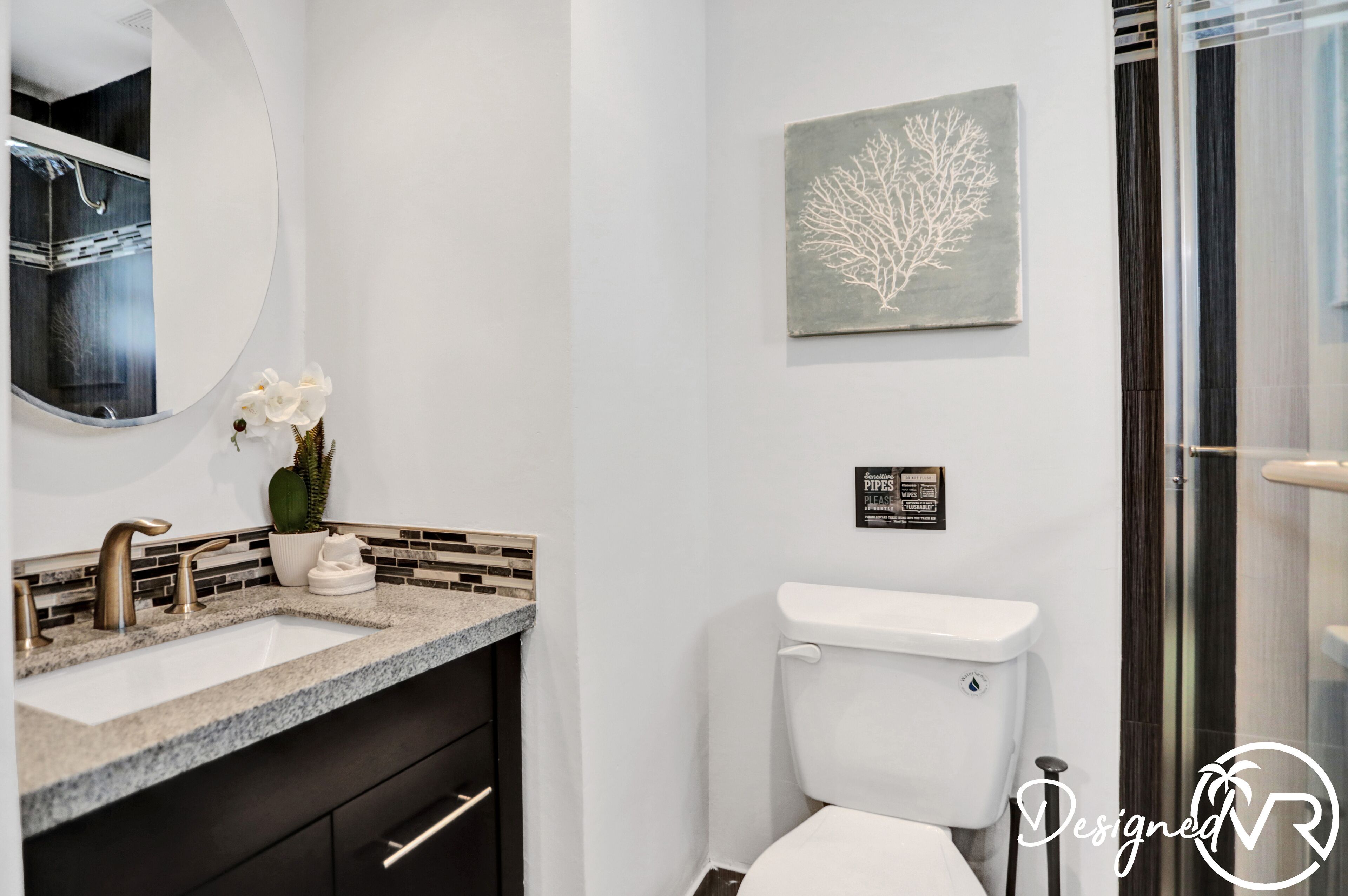 Een moderne badkamer met een wit wastafel, een grote spiegel, een toilet en een douchegedeelte.