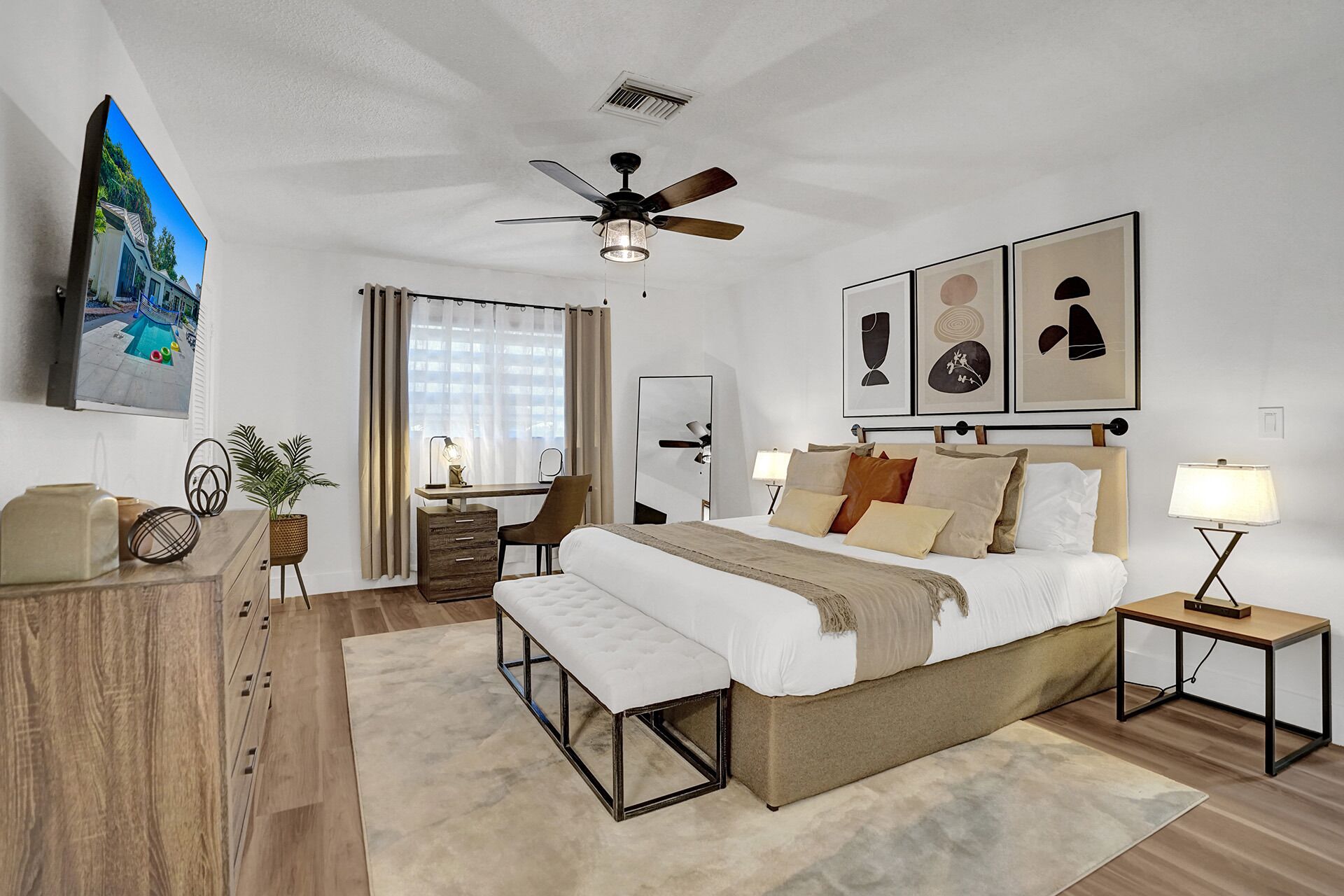Un dormitorio moderno con una cama grande, mesitas de noche, un escritorio y un ventilador de techo.