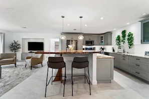 Une cuisine moderne dotée d’un îlot central, de tabourets de bar et d’un coin repas avec des chaises.
