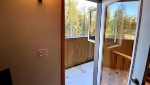 Ein Zimmer mit einer Holterrasse, einer Glastür, die nach draußen führt, und einer Wandleuchte.