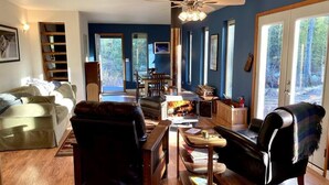 Ein gemütliches Wohnzimmer mit Kamin, Ledersesseln, einem Couchtisch und einem Bücherregal.