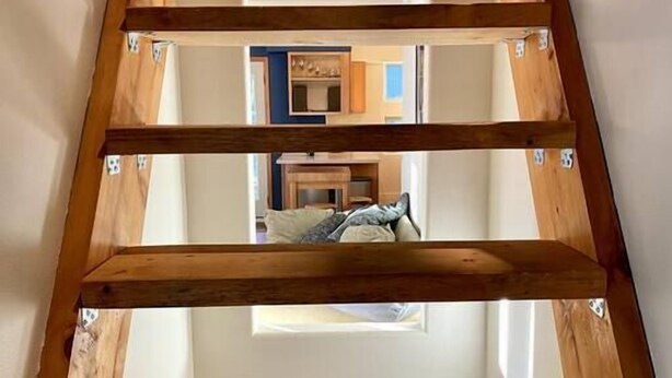 Eine Holztreppe mit Blick auf einen Raum oben.
