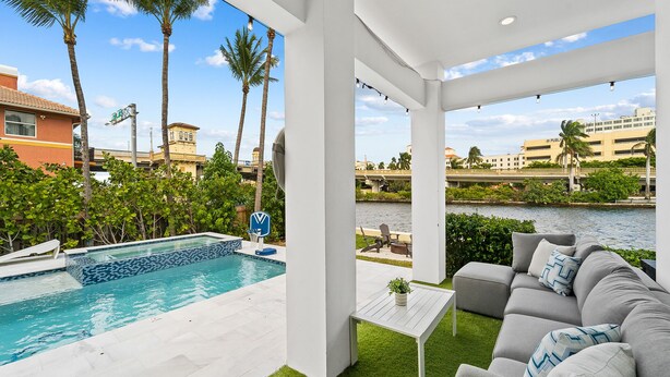 A covered outdoor area with a pool, a sofa, and a table. - Intercostal beauty with heated pool + Spa! (Hollywood)