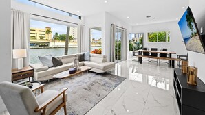 A modern living room with a sofa, coffee table, and TV. - Intercostal beauty with heated pool + Spa! (Hollywood)