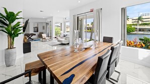 A modern dining area with a wooden table, chairs, and a view of a body of water. - Intercostal beauty with heated pool + Spa! (Hollywood)