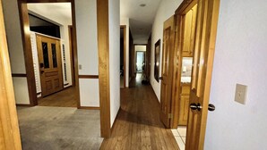 Un pasillo con puertas de madera, suelo alfombrado y pared de azulejos.