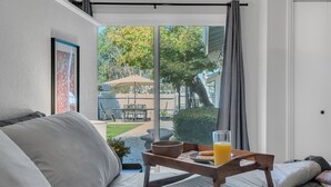 A bedroom with a large window, a bed, a tray with breakfast items, and a view of the outside. - Large home - Sleeps many 4B/2B (Walnut Creek)