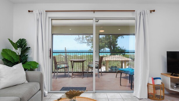 Un salon avec un canapé, un téléviseur et un balcon équipé d’une table et de chaises.