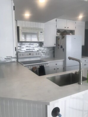 Eine moderne Küche mit weißen Schränken, einem Edelstahlspülbecken und einem eingebauten Backofen.
