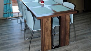 En matplats med ett bord, stolar, en kaffebryggare och utsikt genom en skjutdörr av glas.