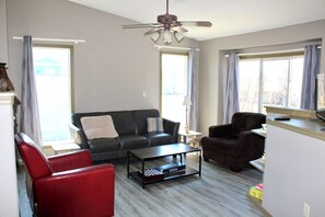A living room with a sofa, armchair, coffee table, and a ceiling fan.