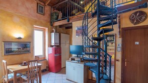 Une cuisine équipée d’une table à manger, de chaises, d’un réfrigérateur, d ’une télévision et d’un escalier en colimaçon.