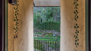 Un couloir donnant sur un jardin grâce à une porte vitrée, agrémenté d’une rambarde en métal et d’un appareil fixé au mur.