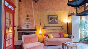 Un salon chaleureux avec une cheminée, une cabine téléphonique rouge et un canapé confortable.
