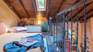 Une chambre avec un plafond en bois, un puits de lumière, un lit avec un magazine, une table de chevet et une vue sur une cabine téléphonique rouge.