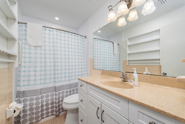 Un baño con inodoro, lavabo y zona de ducha.