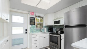 Een moderne keuken met witte kastjes, roestvrijstalen apparatuur en een betegelde achterwand.