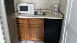 A compact kitchenette with a microwave, coffee maker, and sink. - Autrain Motel (Au Train)