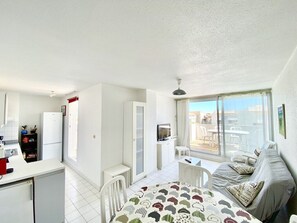 Un appartement compact doté d’une kitchenette, d’un coin repas, d’un lit et d’un balcon avec vue.
