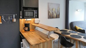 Eine kleine Küche mit Mikrowelle, Kaffeemaschine und einem Holztisch mit Stühlen.