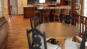 A kitchen with wooden cabinets, a white refrigerator, a dining table with chairs, and a ceiling fan. - Woof Pack Shack  #3 (West Leyden)