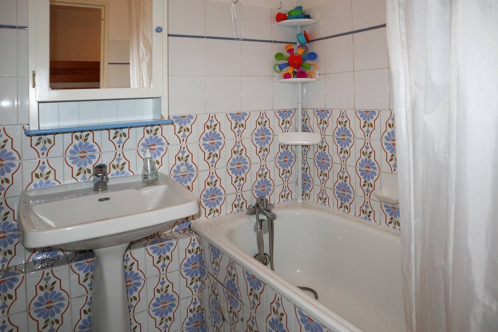 Ein Badezimmer mit Waschbecken, Badewanne und einem Regal mit bunten Gegenständen.